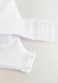 Los cierres de tela blanca cuentan con botones de presión ajustables en los bordes, con una textura suave y costuras cosidas para mayor durabilidad.