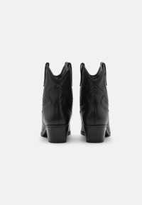 Zwarte leren laarzen met een gestapelde hak, voorzien van decoratieve stiksels en trekbanden aan de achterkant voor gemakkelijk aan- en uittrekken. Gladde textuur, spitse vorm.