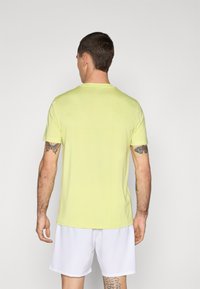 Kortermet skjorte i lys gul stoff, med en enkel rund halslinje og minimalistisk design med en jevn tekstur.