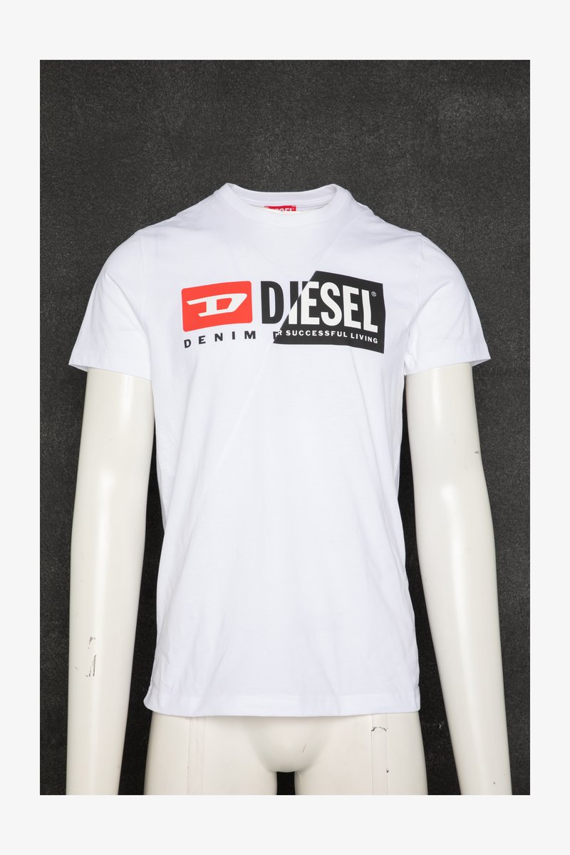 Camiseta blanca de manga corta con un logotipo llamativo de "DIESEL" en negro y rojo, con el texto "DENIM" y "SUCCESSFUL LIVING" debajo. Tela suave.