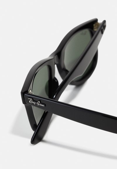 Черен слънчеви очила Ray-Ban с ъглови рамки, тъмнозелени лещи и сребрист акцент на логото на темпелите. Гладка текстура.