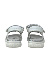 Sandali bianchi con suola texturizzata, caratterizzati da una finitura liscia e cinturini regolabili. I dettagli metallici lungo la suola aggiungono un delicato luccichio.