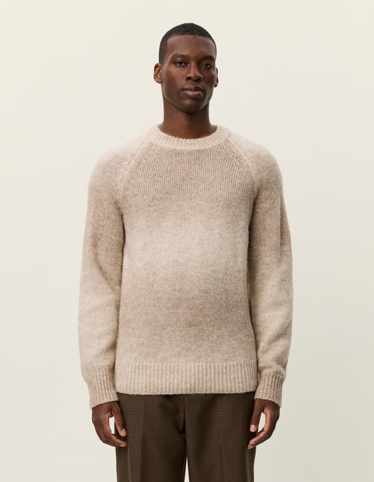 Beige neulepaita, jossa on liukuvärjäys, raglan-hihat ja ribatut hihansuut, valmistettu pehmeästä, teksturoidusta materiaalista.