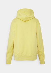 Gul hoodie med dragsko i huvan, med en mjuk textur, ribbade ärmar och en något oversized passform. Bakifrån visas en sömlös design.