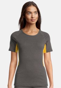 T-shirt sportivo grigio e giallo con maniche corte, design aderente, scollatura a girocollo e pannelli laterali a contrasto in un tessuto testurizzato.