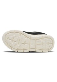 Zapatilla atlética negra con un upper texturizado negro y una suela de goma blanca. Presenta un desgaste con patrón para agarre y estabilidad.