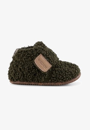 Grønne teksturerede slippers med blød, fuzzy overdel, brun gummisål og et tan lædermærke, der viser "WODEN." Velcro-lukning for nem påtagning.