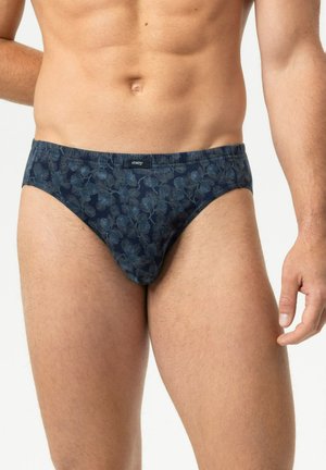 Männlicher Oberkörper trägt dunkelblaue, floral gemusterte Slips mit einem kleinen "mey"-Label am Bund, stehend vor einem einfarbigen Hintergrund.