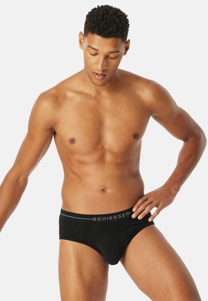 Schwarze Baumwollslips mit glattem Stoff, ausgestattet mit einem grauen Logo-Bund und einem konturierten Pouch-Design für Unterstützung und optimalen Sitz.