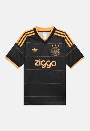 Maillot de football noir et orange avec logo Ziggo, emblème Adidas, trois étoiles et écusson circulaire de l'équipe sur la poitrine, avec des rayures orange sur les manches.