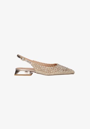 Zapato plano beige con punta, de tipo slingback, con tacón ancho metálico y cubierto de adornos redondos brillantes sobre una parte superior de malla.