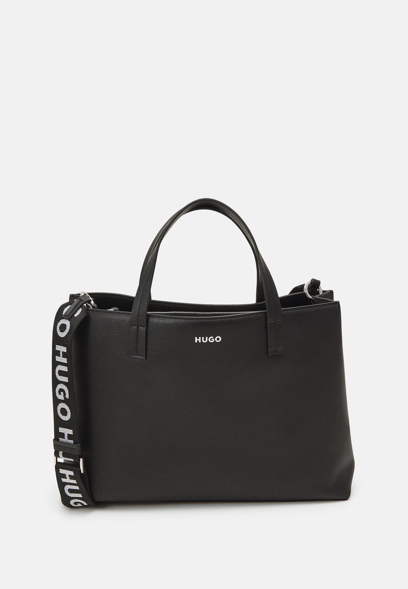 Black leather tote bag with dual top handles and detachable strap featuring a logo on the front and textured surface. Zipper closure detail.