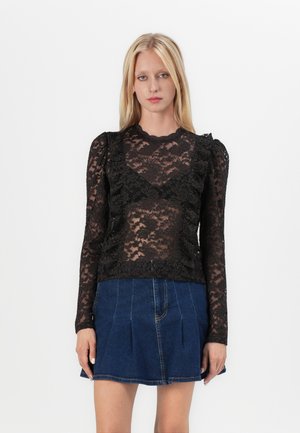 Svart blondebluse med lange ermer, bølget utskjæring, volanger på sidene, kombinert med en jeansskjørt.