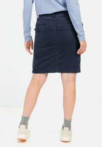 Jeans-Bleistiftrock in Dunkelblau, mit figurbetontem Schnitt, elastischem Bund und Gesäßtaschen, kombiniert mit einem hellblauen Langarmoberteil.