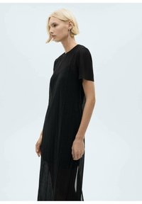 Črna nabrana obleka s kratkimi rokavi, ki ima sproščen kroj in stranska razporka. Lahkoten, prozoren material poudarja plaste našega dizajna.