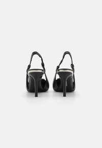 Mustad musta värvi slingback sokkidega kõrge kontsaga kingad, läikiva pinnaga, õhuke stilettokonts ja kootud rihmadega detail. Sile tekstuur ja avatud varba disain.