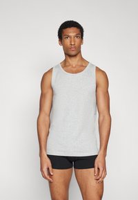 Graues Baumwoll-Top mit rundem Ausschnitt und weiten Armausschnitten, mit glatter Textur und schlichtem Design, getragen mit schwarzen Shorts.