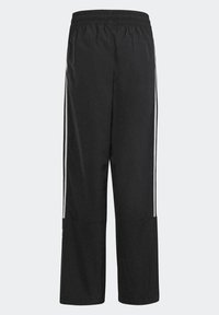 Czarne spodnie sportowe z elastycznym pasem, szczelinami po bokach u dołu i białymi paskami wzdłuż boków. Lekkie, gładkie w dotyku.