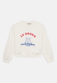 Sweatshirt cor de creme com design cropped. Apresenta texto vermelho e azul dizendo "LE BRONX, New York City, LIFE OF CURIOSITY" e duas ilustrações de coelhos.