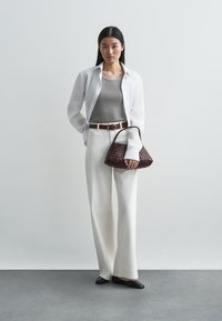 Chemise blanche, débardeur gris, pantalon large blanc, ceinture marron, sac tissé marron, ballerines noires, textures lisses, design minimal.