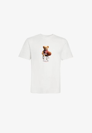 Hvid T-shirt med grafik af en tøjdyrsbjørn iført en basketballtrøje, der holder en basketball og sneakers, centreret foran.