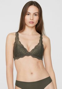 Reggiseno verde oliva in pizzo con motivo floreale, coppe morbide, bordi smerlati e spalline regolabili. Tessuto liscio e leggero.