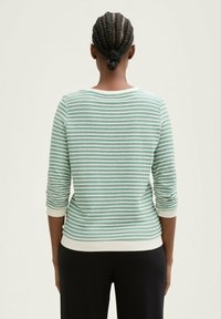 Grün-weiße gestreifte Pullover mit Dreiviertelärmeln. Mit rundem Halsausschnitt und weißen Bündchen. Weiches, strukturiertes Material.