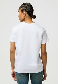 Hvid bomulds T-shirt med korte ærmer og rund halsudskæring, der har en glat tekstur og en almindelig pasform. Bagfra set.