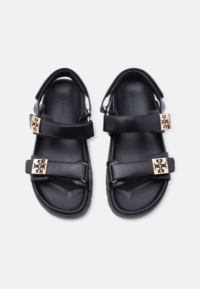 Μαύρα δερμάτινα σανδάλια με διπλά ρυθμιζόμενα λουριά και επίχρυσα αγκράφα, επίπεδη σόλα, σχεδιασμός με ανοιχτά δάχτυλα.