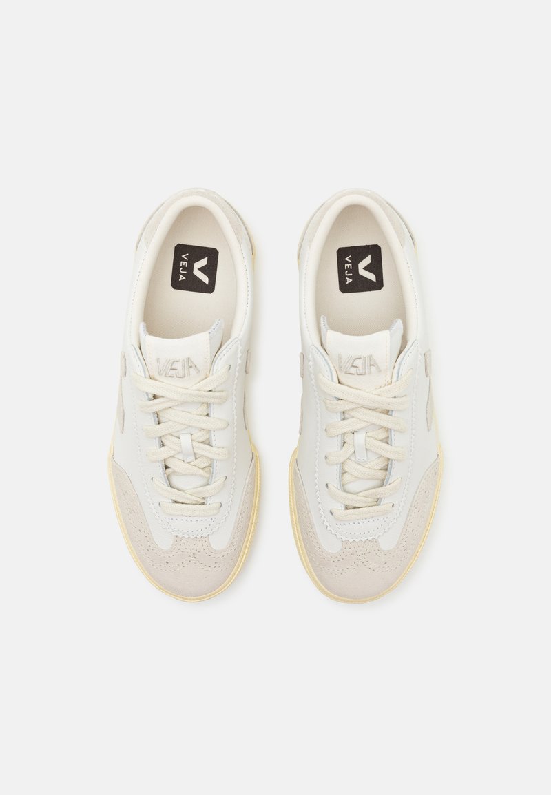 Baskets avec un dessus en cuir et daim crème, accents beiges, lacets beiges et semelle en caoutchouc texturée. Logo sur la languette. Silhouette classique.