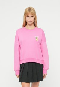 Ροζ φούτερ με άνετη  εφαρμογή, ριμπ μανσέτες και λαιμόκοψη γύρω από το λαιμό. Διαθέτει λογότυπο "FRESH" και γραφικό φύλλο στο αριστερό μέρος του στήθους.