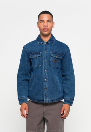 Denim jacket in medium blue featuring a collared neckline, button front, two chest pockets with flaps, and side hand pockets.