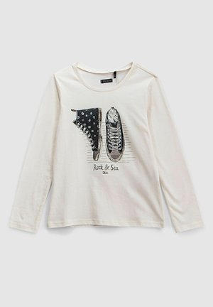 Creme langærmet skjorte med grafik af sorte prikker og ensfarvede sneakers samt teksten "Rock & Sea" foran.