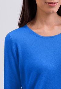 Maglione blu lavorato a maglia con scollo tondo e maniche lunghe. Texture morbida, vestibilità slim e cuciture minime per un design pulito.