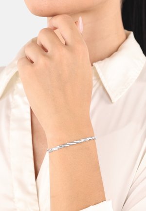 Bracciale intrecciato d'argento indossato su un polso, caratterizzato da un design elegante con una finitura in metallo lucido e una texture liscia.