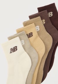 Σετ έξι ριγωτές κάλτσες σε διάφορες αποχρώσεις: εκρού, ανοιχτό μπεζ, μπεζ, ταμπά, σκούρο καφέ και βαθύ σοκολατί, κάθε μία με καφέ λογότυπο.