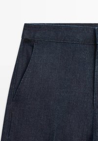 Dark blue denim pants with a smooth texture, featuring a waistband, side pockets, and subtle stitching details.