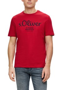 Rood katoenen T-shirt met een ronde hals, korte mouwen, en een zwart bedrukt logo met de tekst "s.Oliver ELEVATED ESSENTIALS SINDS 1969."
