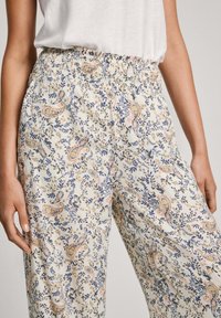 Pantalones sueltos y ligeros con una cintura elástica, que presentan una base crema y patrones florales y de paisley en tonos azules y melocotón.