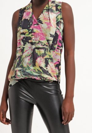 Sleeveless floral patterned top with green, pink, and black colors worn with shiny black leather pants on a standing person.