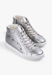 Zapatillas altas plateadas hechas de cuero metálico, con cordones, cremallera lateral, adornos de tachuelas y suelas de goma blanca.