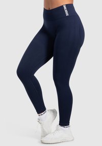 Leggings high-waisted di colore blu navy con una texture liscia e una cintura spessa con il logo "SMILODON". Adatti per abbigliamento sportivo.