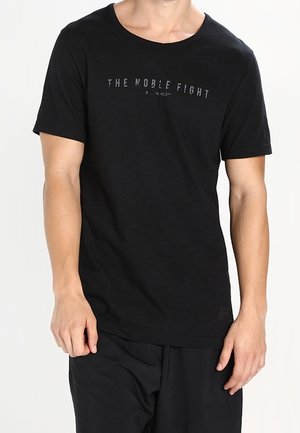 Man draagt een zwart T-shirt met korte mouwen waarop in grijs de tekst "THE NOBLE FIGHT" staat gedrukt over de borst.