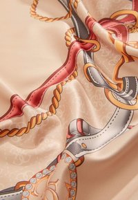 Foulard di seta con sfondo beige caratterizzato da un motivo di corde e catene in rosso, arancione, grigio e accenti dorati.