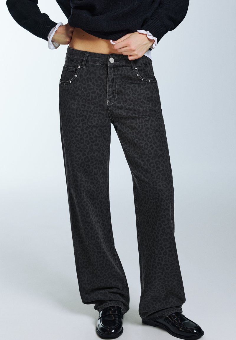 Svarta vida jeans med leopardmönster, framfickor och metallicnitar som detaljer. Slät denimstruktur med avslappnad passform.