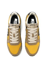 Zapatillas amarillas y beige que combinan materiales de malla y gamuza, punta redonda, cordones crema, acentos negros y una suela de goma texturizada.