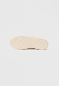 Sål av en beige joggesko med geometrisk mønster, merkenavnet "Tamaris" og størrelsenummer 36 synlig på siden.