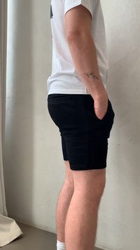 Pantaloni corti neri dalla vestibilità slim e con tasche laterali, realizzati in un tessuto morbido. Indossati con una maglietta bianca e calzini bianchi. Design semplice e moderno.