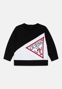 Svart og hvit sweatshirt med en stor rød trekantet logo med "GUESS U.S.A." brodert foran. Den har rund hals og lange ermer.