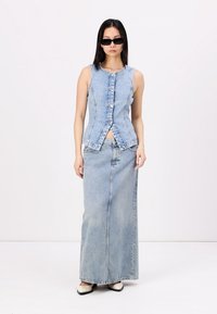 Lichtblauw denim mouwloos topje met knoopsluiting, gecombineerd met een lange, bijpassende denim rok. Gladde textuur, casual ontwerp.